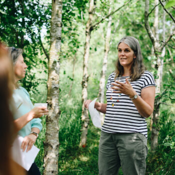 Photograph of Claire running an outdoor coaching retreat among silver birch trees in June