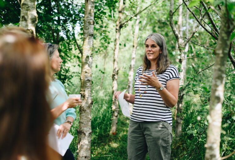 Photograph of Claire running an outdoor coaching retreat among silver birch trees in June